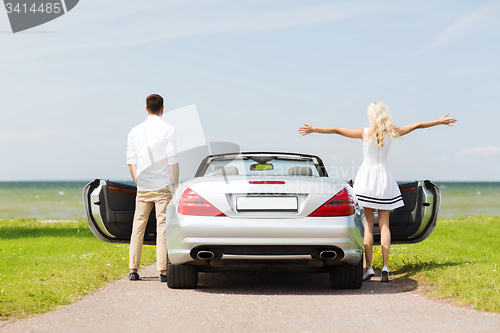 Image of happy man and woman near cabriolet car at sea