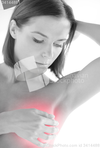 Image of woman checking breast for signs of cancer