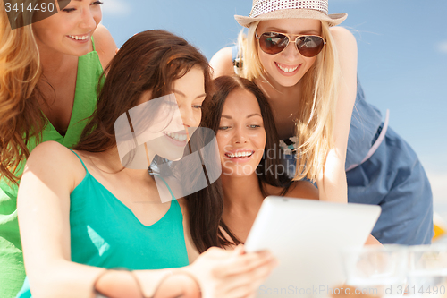 Image of smiling girls looking at tablet pc in cafe
