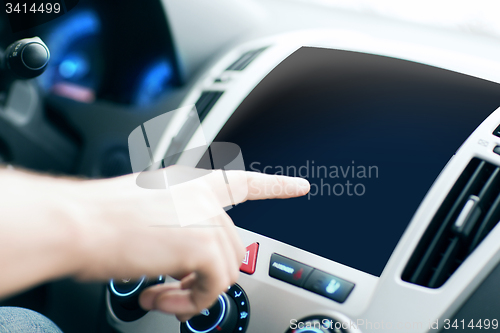 Image of male hand pointing finger to monitor on car panel