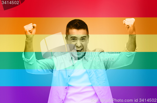 Image of angry man with raised hands over rainbow flag