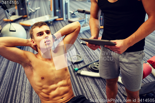 Image of men flexing abdominal muscles in gym