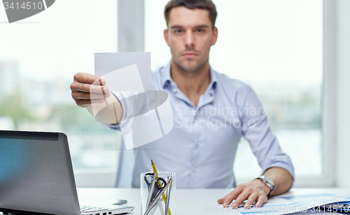 Image of businessman showing blank paper card at office
