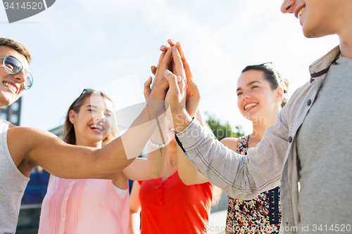 Image of close up of happy friends making high five gesture