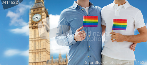 Image of close up of male gay couple with rainbow flags