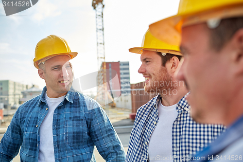 Image of group of smiling builders in hardhats outdoors