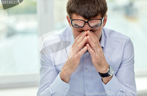 Image of tired businessman with eyeglasses in office