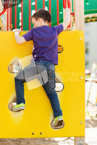 Image of happy little boy climbing on children playground