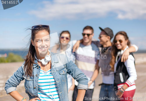 Image of teenage girl with headphones and friends outside