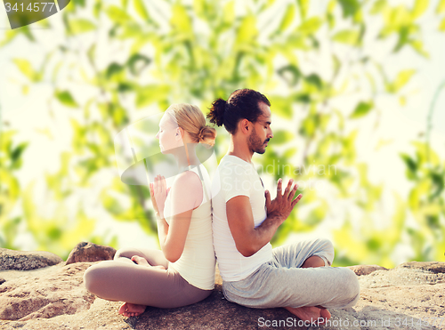 Image of smiling couple making yoga exercises outdoors