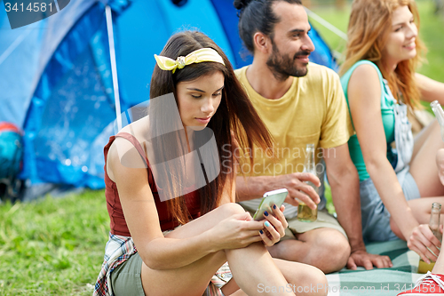 Image of happy woman with smartphone and friends at camping