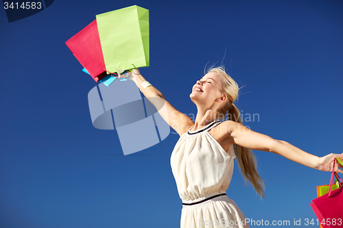 Image of smiling woman with shopping bag rising hands