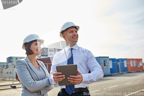 Image of happy builders in hardhats with tablet pc outdoors