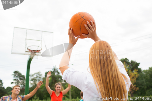 Image of group of happy teenagers playing basketball