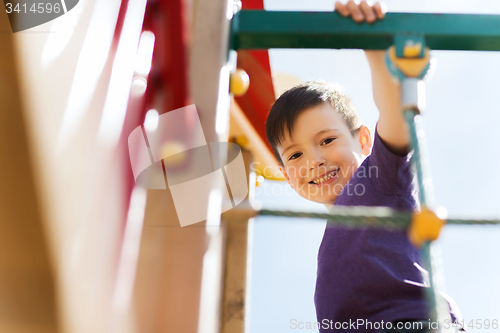 Image of happy little boy climbing on children playground