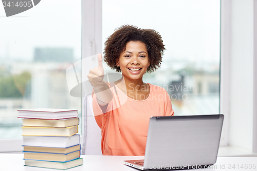 Image of happy african american woman with laptop at home