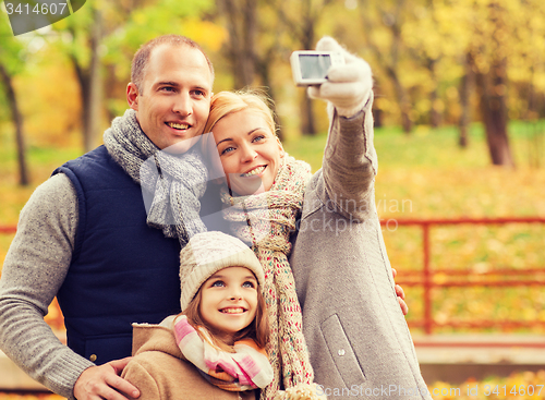 Image of happy family with camera in autumn park