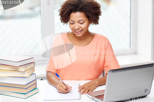 Image of happy african american woman with laptop at home