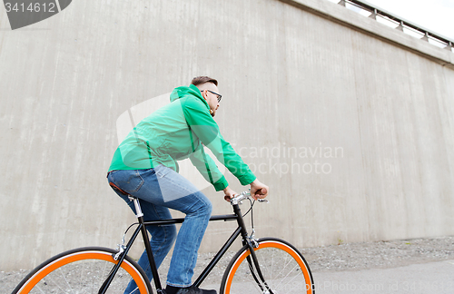 Image of happy young hipster man riding fixed gear bike