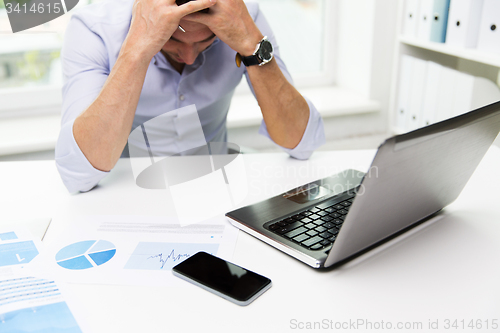 Image of businessman with laptop and papers in office