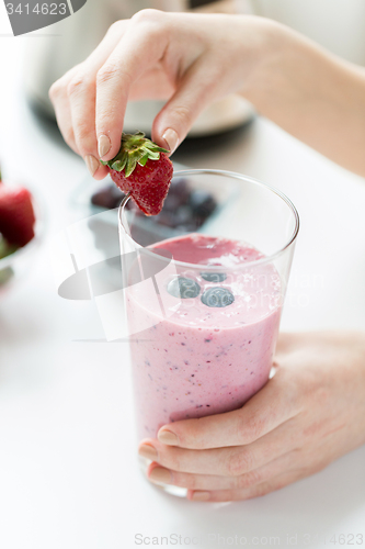 Image of close up of woman with milkshake and strawberry