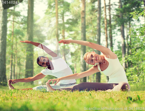 Image of happy couple stretching and doing yoga exercises