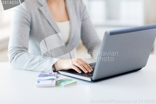 Image of close up of woman hands with laptop and money