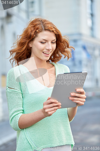 Image of smiling teenage girl with tablet pc on city street