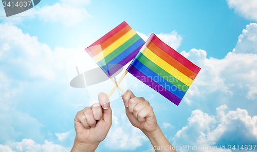 Image of hands holding rainbow flags over sky background