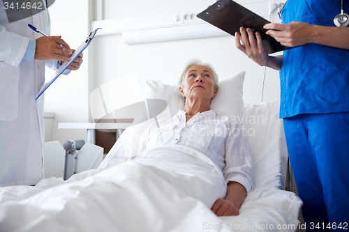 Image of doctor and nurse visiting senior woman at hospital