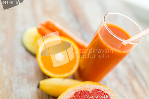 Image of close up of fresh juice glass and fruits on table