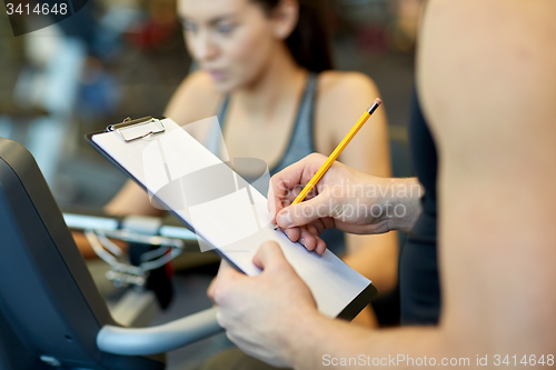 Image of close up of trainer hands with clipboard in gym