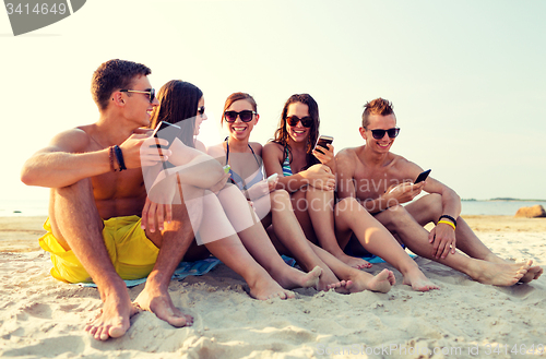 Image of friends with smartphones on beach