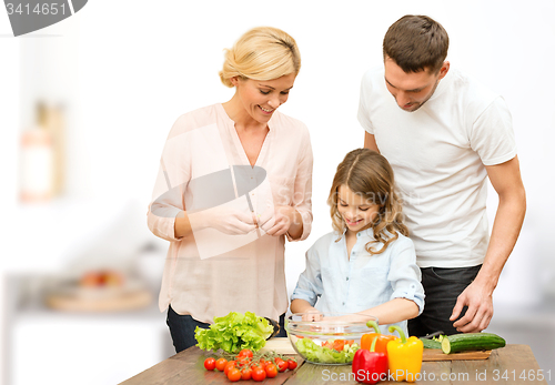 Image of happy family cooking vegetable salad for dinner