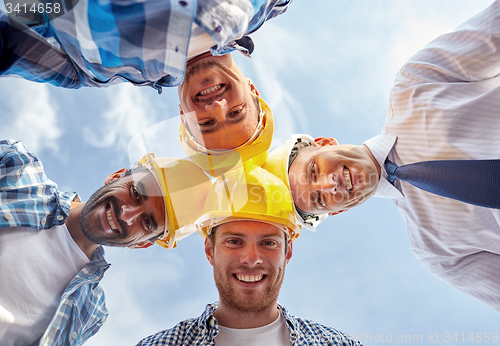 Image of close up of builders wearing  hardhats in circle