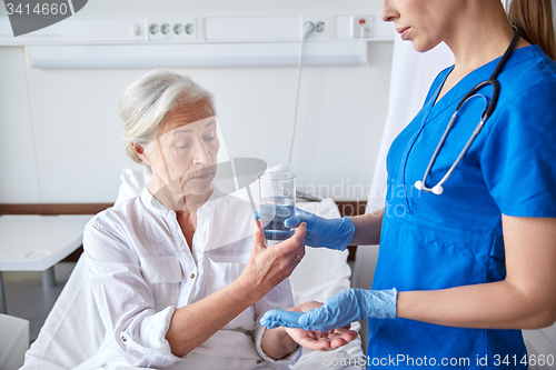 Image of nurse giving medicine to senior woman at hospital