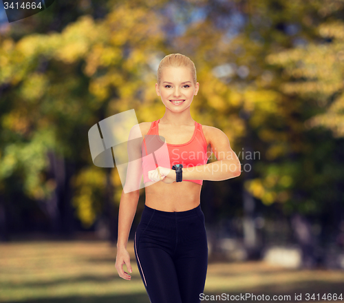 Image of smiling woman with heart rate monitor on hand