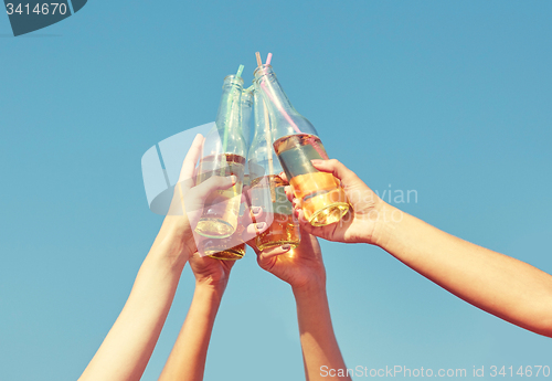 Image of close up of many hands clinking bottles