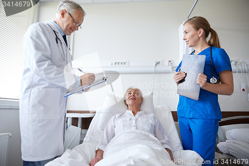 Image of doctor and nurse visiting senior woman at hospital