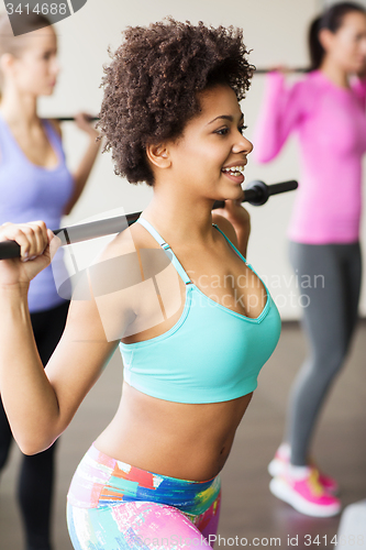 Image of group of people exercising with bars in gym