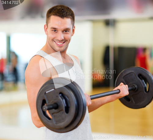Image of smiling man with barbell in gym