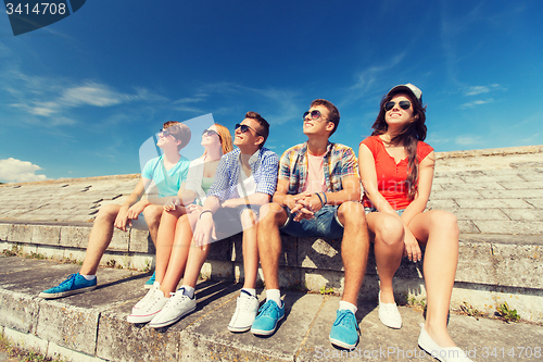 Image of group of smiling friends sitting on city street