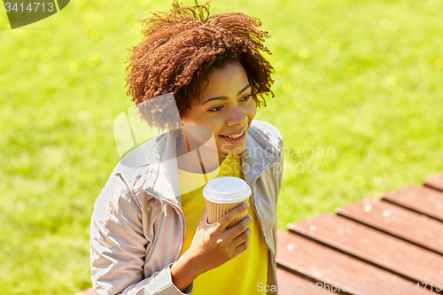 Image of smiling african woman drinking coffee outdoors 