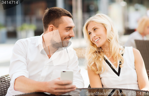 Image of happy couple with smatphone at city street cafe