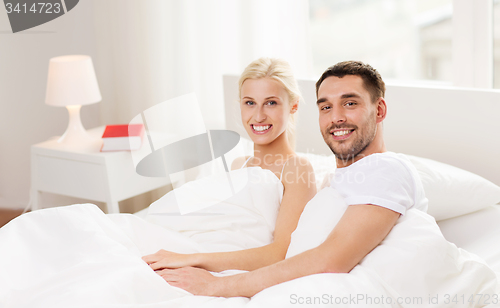 Image of happy couple lying in bed at home