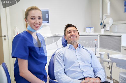 Image of happy female dentist with man patient at clinic