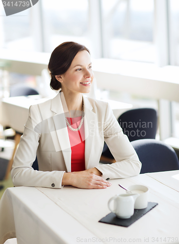 Image of happy woman sitting at table in restaurant