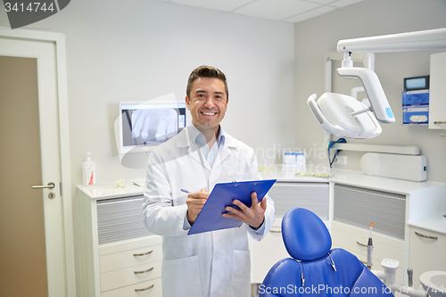 Image of happy male dentist with clipboard at dental clinic