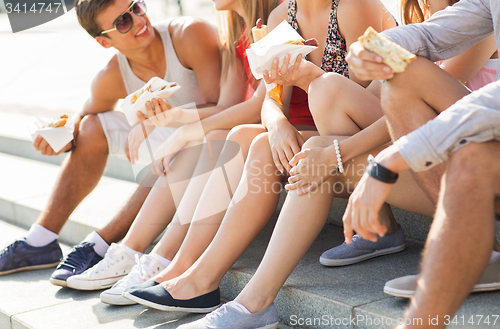 Image of happy friends eating takeout fast food in city 