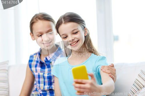 Image of happy girls with smartphone taking selfie at home